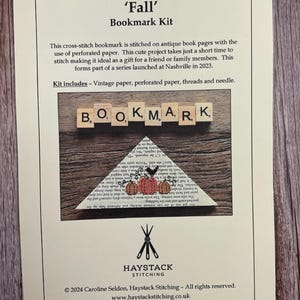 May include: A 'Fall' Bookmark Kit with cross-stitch design. The kit includes vintage paper, perforated paper, threads, and a needle. The bookmark features a stitched design of pumpkins and the word 'BOOKMARK'.
