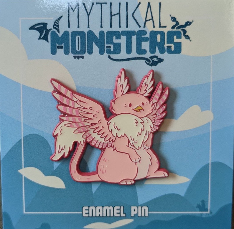 May include: Pink enamel pin depicting a mythical creature with wings, a fluffy tail, and a beak. The pin is displayed against a blue and white background with the text "Mythikal Monsters" and "Enamel Pin".