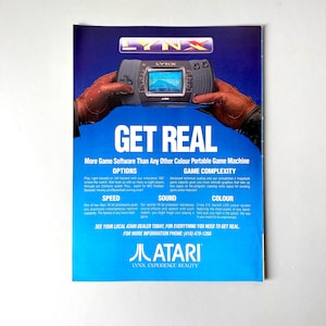 May include: A blue and yellow LYNX handheld games console with a black and white screen. The console is being held by two hands wearing gloves. The text "GET REAL" is in large white letters above the console. The text "More Game Software Than Any Other Colour Portable Game Machine" is below the console. The text "LYNX EXPERIENCE REALITY" is at the bottom of the image.