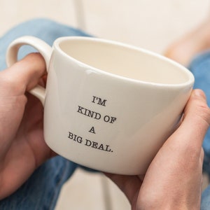 Può includere: Una tazza in ceramica bianca con testo nero che dice "Sono un po' un gran problema."