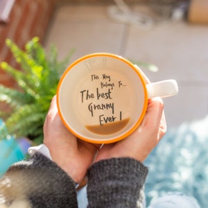 May include: A yellow and white ceramic mug with the text "This Mug Belongs To... The Best Granny Ever!" written on it.