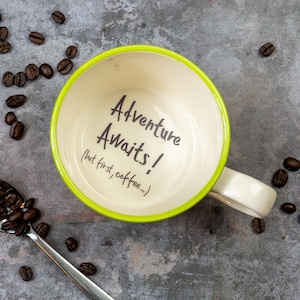 Może przedstawiać: Zielony i biały ceramiczny kubek do kawy z nadrukiem "Adventure Awaits! (but first, coffee...)" wewnątrz.