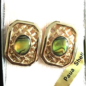 May include: A pair of gold-toned clip-on earrings with a woven design around an oval, iridescent center. The earrings are presented in a white box with a gold label that reads "Paua Shell".