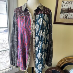 May include: A long-sleeved button-up shirt with a patchwork design. The shirt is made of different fabrics with various patterns, including black and white polka dots, teal and white bird prints, and pink and purple floral designs.