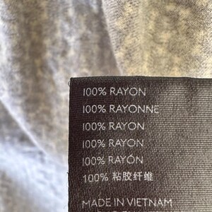 May include: A black fabric label with white text that reads "100% RAYON", "100% RAYONNE", "100% RAYON", "100% RAYON", "100% RAYON", "100% 粘胶纤维", and "MADE IN VIETNAM".