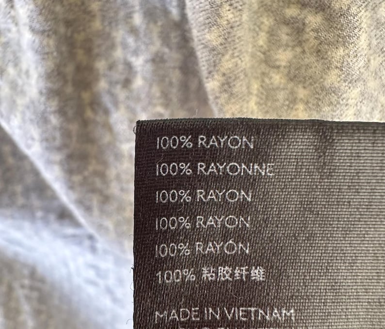May include: A black fabric label with white text that reads "100% RAYON", "100% RAYONNE", "100% RAYON", "100% RAYON", "100% RAYON", "100% 粘胶纤维", and "MADE IN VIETNAM".