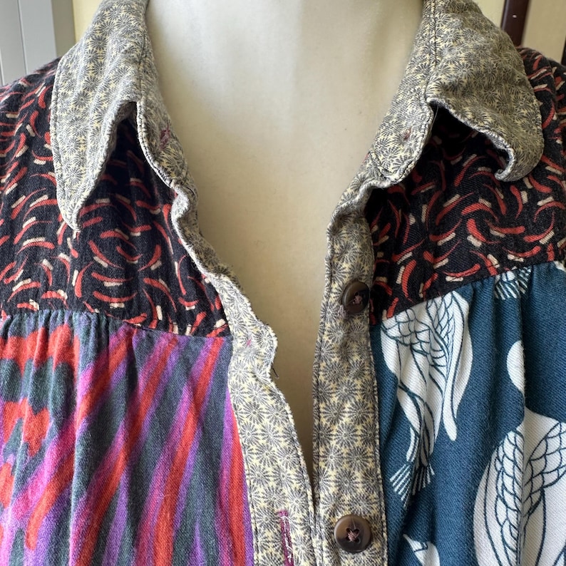 May include: A patchwork button-up shirt with a variety of colorful patterns, including floral, geometric, and abstract designs. The shirt has a collar and a button-up front.