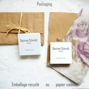 Pode incluir: Duas op&ccedil;&otilde;es de embalagem para um produto. A primeira op&ccedil;&atilde;o &eacute; um envelope de papel castanho amarrado com um cord&atilde;o. A segunda op&ccedil;&atilde;o &eacute; um saco de papel castanho com papel de seda estampado floral no interior. Ambas as op&ccedil;&otilde;es incluem uma caixa branca com o texto "Desiree Schmidt Paris" e o endere&ccedil;o do site "www.desiree-schmidt.com". O texto "Packaging" est&aacute; no topo da imagem. O texto "Emballage recycl&eacute; ou papier cadeau" est&aacute; na parte inferior da imagem.