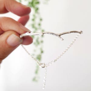 Peut inclure: Un bracelet en argent avec un délicat motif de brindille. Le bracelet est réglable avec une chaîne et un fermoir.