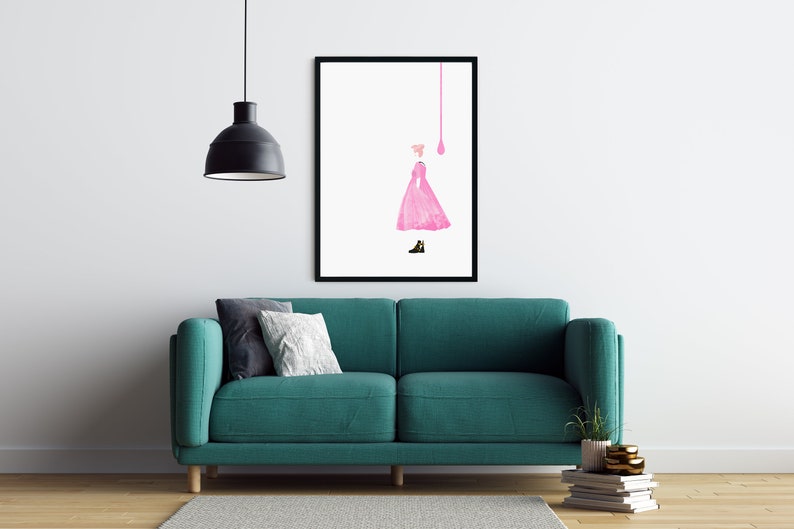 Puede incluir: Una impresi&oacute;n art&iacute;stica enmarcada que presenta una ilustraci&oacute;n de un vestido rosa y un zapato negro. La obra de arte est&aacute; sobre un fondo blanco. La habitaci&oacute;n incluye un sof&aacute; turquesa, almohadas, una l&aacute;mpara colgante negra y una pila de libros.