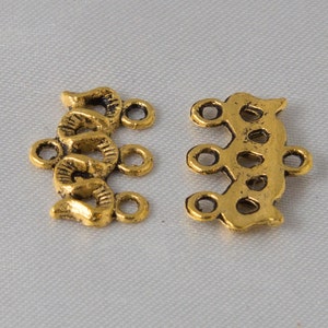 May include: Two gold-tone metal connector pieces for jewellery making. Each piece has a decorative design and multiple loops for attaching chains or cords.