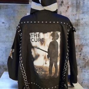May include: Black hooded jacket with silver grommets and a graphic print of The Cure band with the text "Boys Don't Cry".