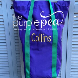 Puede incluir: Bolsa de lona morada con correas verdes y el texto "the purple pea monogram & embroidery boutique Collins" bordado en dorado.