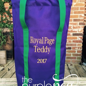 Puede incluir: Bolsa de tela morada con correas verdes y el texto "Royal Page Teddy 2017" bordado en dorado. La bolsa est&aacute; hecha por "the purple pea monogram & embroidery boutique".