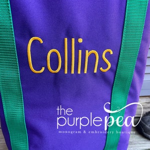 Puede incluir: Bolsa de lona morada con correas verdes y el nombre "Collins" bordado en amarillo. La bolsa tiene el texto "the purple pea monogram & embroidery boutique" impreso en la parte inferior.