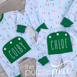 May include: Two pairs of light blue pajamas with a bunny and carrot print. One pair has a green pocket with the name "COLBY" embroidered on it. The other pair has a green pocket with the name "CHLOE" embroidered on it.