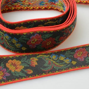 May include: A black and red ribbon with a floral pattern. The ribbon is woven with colorful threads and has a red border.