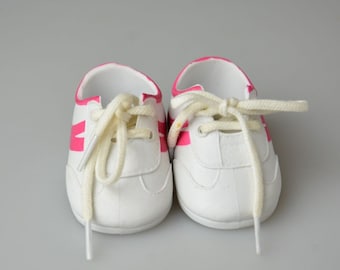 Puede incluir: Un par de zapatillas blancas con detalles en rosa y cordones blancos.