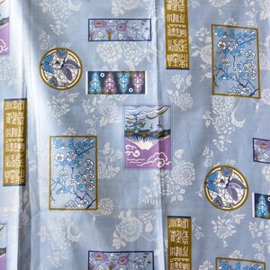 May include: A blue fabric with a repeating pattern of white flowers, butterflies, and Japanese characters. The characters are in a gold rectangle and read "金魚", which means goldfish.