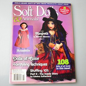 May include: Soft Dolls & Animals magazine cover featuring a witch doll with a purple and red dress, a black hat, and a book. The magazine cover also features a smaller doll with a red dress and a title that reads "Dolls of Color Hairstyling Techniques".