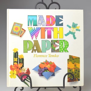 May include: A colorful book titled "Made With Paper" by Florence Temko. The cover features a variety of paper crafts, including origami flowers, a teddy bear, and a box.