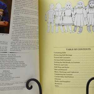 Pode incluir: Uma tabela de conte&uacute;do para um livro sobre o figurino de bonecas. O livro abrange t&oacute;picos como a preserva&ccedil;&atilde;o do patrim&ocirc;nio de bonecas, os trajes de bonecas francesas, os trajes de bonecas alem&atilde;s, a prepara&ccedil;&atilde;o da boneca para o figurino, os padr&otilde;es e a cor, as perucas e os estilos de bonecas, os chap&eacute;us e os gorros, os sapatos, as meias e a roupa interior, a conclus&atilde;o do figurino, o padr&atilde;o de boneca de croch&ecirc;, o gloss&aacute;rio, os livros e os folhetos, os recursos e o &iacute;ndice.