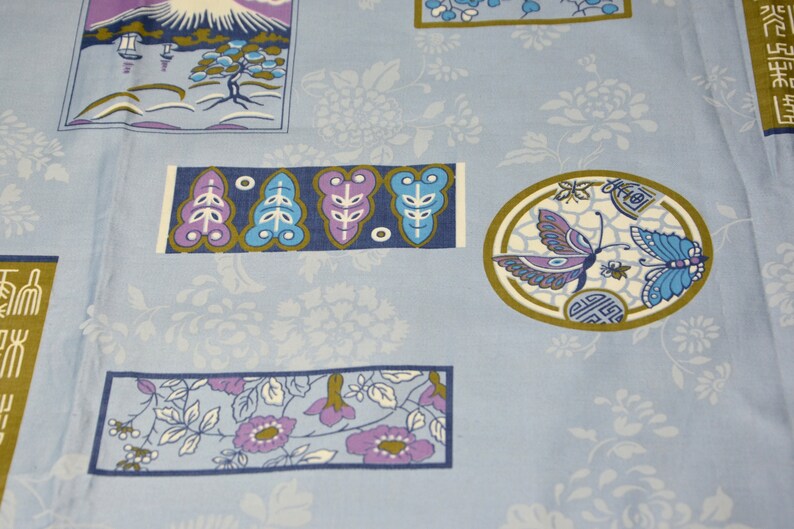 May include: A blue fabric with a repeating pattern of flowers, butterflies, and Japanese-inspired designs. The fabric features a mountain scene, stylized leaves, and a butterfly in a circle.