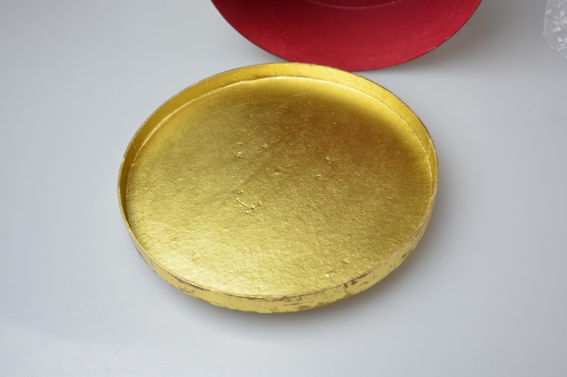 May include: A round, gold-colored lid for a box. The lid is made of cardboard and has a smooth, shiny surface.
