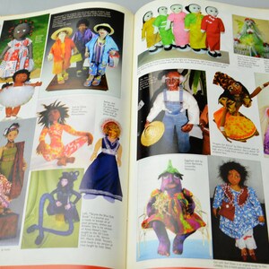 May include: A collection of handmade dolls in various styles and colors. The dolls are dressed in colorful clothing and have unique facial features. Some dolls are holding props, such as a hat or a flower. The dolls are displayed on a white background.