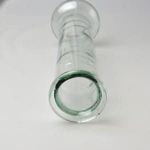 K&ouml;nnte beinhalten: Transparente Glasvase mit breitem, abgerundetem Oberteil und zylindrischem K&ouml;rper. Die Vase hat einen ausgestellten Boden und eine glatte, transparente Oberfl&auml;che. Das Design ist schlicht und elegant, geeignet f&uuml;r Blumen oder als Dekoration.