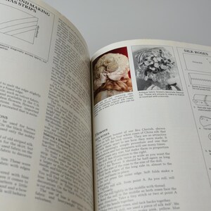 Pode incluir: Um livro vintage aberto em uma p&aacute;gina sobre como fazer rosetas de seda. A p&aacute;gina inclui instru&ccedil;&otilde;es e diagramas sobre como fazer as rosetas. O livro tamb&eacute;m tem uma se&ccedil;&atilde;o sobre como fazer flores de seda.