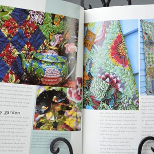 May include: A book spread showcasing quilts and a decorative teapot. The quilts feature detailed floral and geometric patterns. The teapot is blue with floral designs. The page is titled "gypsy garden".