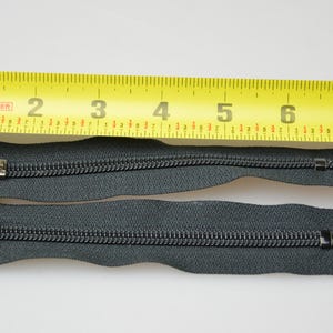 May include: Two black zipper pulls with silver sliders, measured against a yellow tape measure. The tape measure reads 20.3 cm.