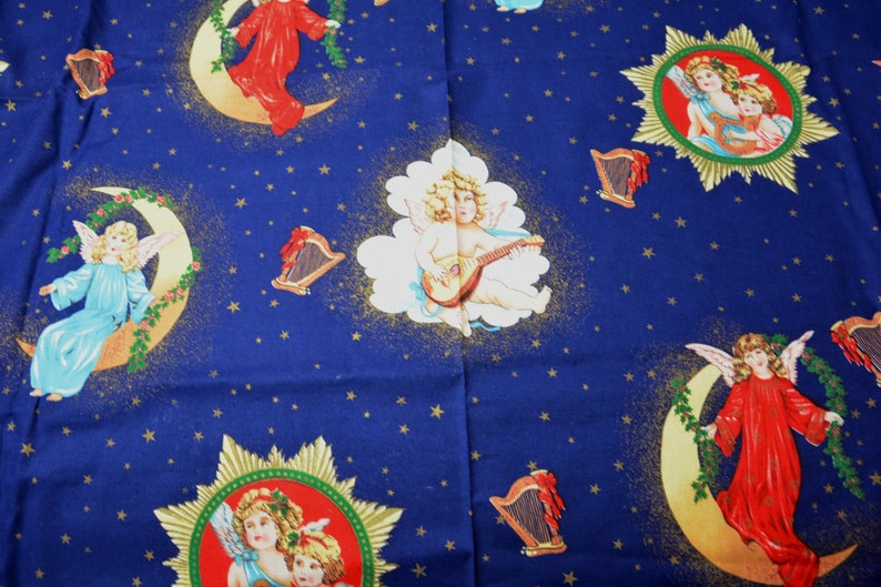 May include: A blue fabric featuring celestial imagery. The design includes angels, moons, stars, and harps. Angels are depicted in various poses and colors, set against a background of gold stars and crescent moons.
