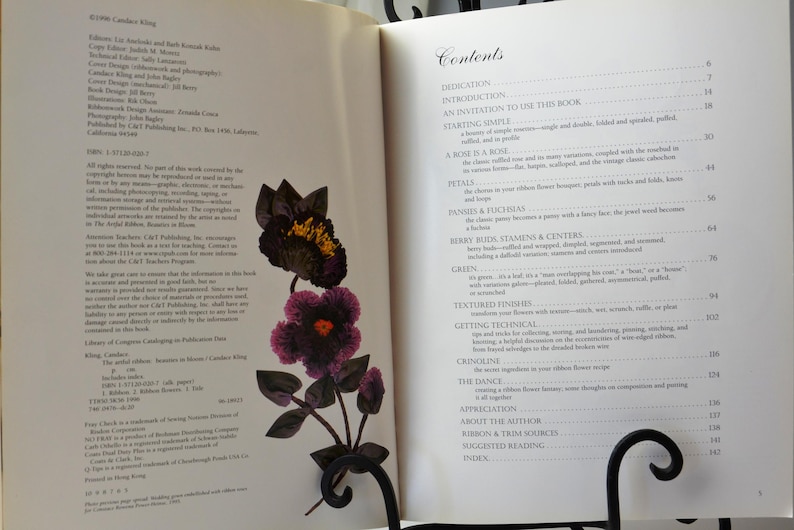 Peut inclure: Un livre intitul&eacute; "Candied Flowers" avec une image rapproch&eacute;e d'une fleur violette et noire en tissu. La couverture du livre pr&eacute;sente une table des mati&egrave;res avec des sujets tels que "Introduction", "P&eacute;tales", "Boutons de baies, &eacute;tamines et centres", "Vert", "Finitions textur&eacute;es", "Techniques d'obtention", "Crinoline", "La danse", "Appr&eacute;ciation", "&Agrave; propos de l'auteur", "Sources de rubans et de garnitures", "Lectures sugg&eacute;r&eacute;es" et "Index".
