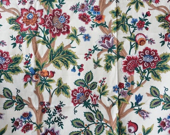 May include: A white fabric with a repeating floral pattern. The pattern features red, blue, and green flowers with brown branches.