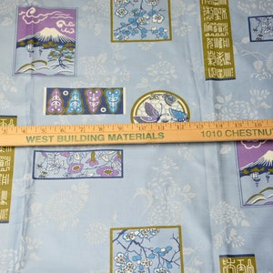 May include: Blue fabric with a repeating pattern of Japanese-inspired designs. The designs include stylized flowers, a mountain, and a butterfly. The fabric also features text in Japanese characters.