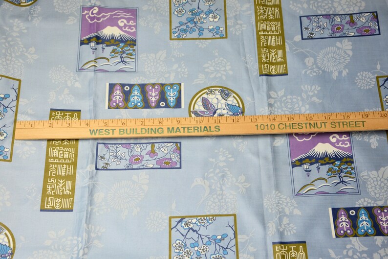 May include: Blue fabric with a repeating pattern of Japanese-inspired designs. The designs include stylized flowers, a mountain, and a butterfly. The fabric also features text in Japanese characters.