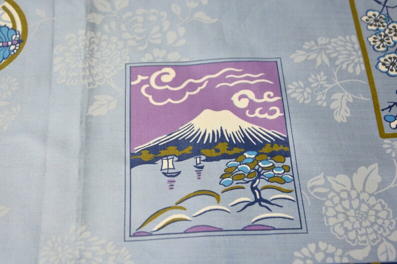 May include: A blue and purple fabric with a white mountain scene, white clouds, and a green tree. The scene is framed in a blue border.