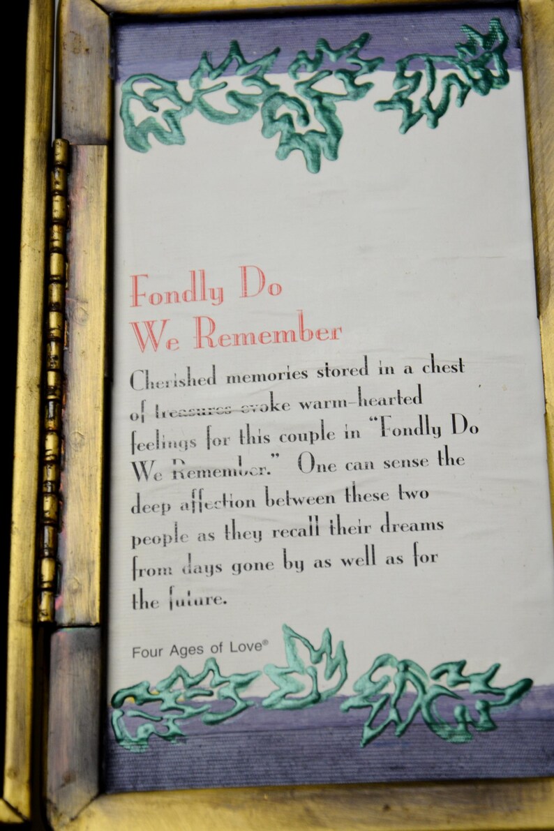 Op de afbeelding: Een ingelijste print met de tekst "Fondly Do We Remember" in rood en zwart. De lijst is goudkleurig met een donkerpaarse rand en groene bladachtige ontwerpen. De tekst beschrijft gekoesterde herinneringen.
