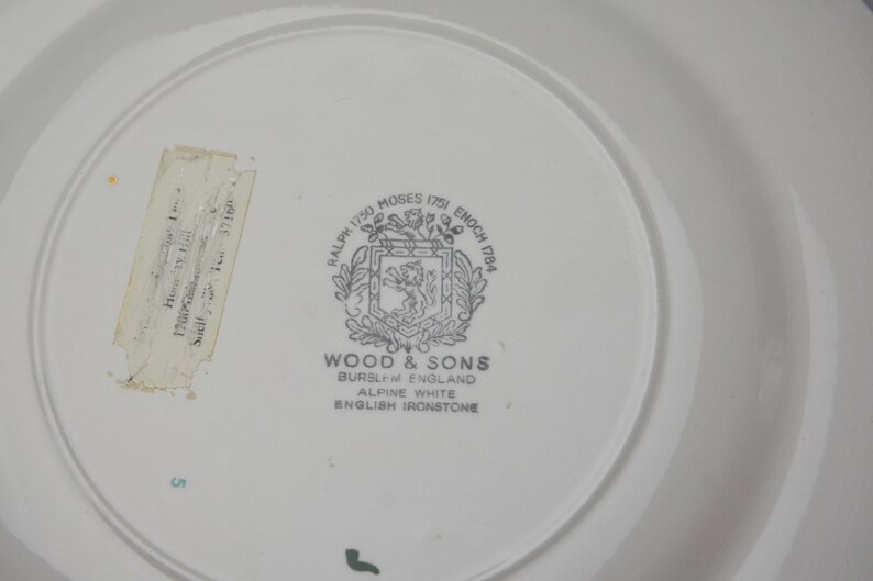 May include: A white ceramic plate with a black and white logo that reads "Ralph 1750 Moses 1751 Enoch 1784", "Wood & Sons", "Burslem England", "Alpine White", and "English Ironstone".