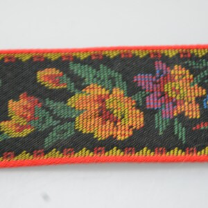 May include: Black fabric trim with a red edge and a floral pattern in shades of yellow, orange, red, green, blue, and purple.