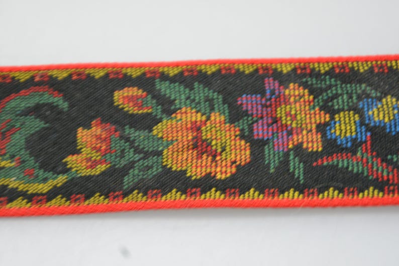 May include: Black fabric trim with a red edge and a floral pattern in shades of yellow, orange, red, green, blue, and purple.