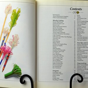 May include: A book titled "Papercraft" with a table of contents listing various paper crafts, including origami, pop-ups, and papermaking techniques. The book cover features colorful paper flowers and a bookmarker.