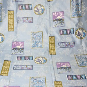 May include: Blue fabric with a repeating pattern of Japanese-inspired designs. The pattern includes Mount Fuji, cherry blossoms, and traditional Japanese characters.