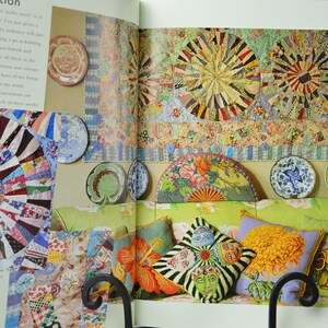 May include: An interior design spread with a patchwork quilt, decorative plates, and patterned cushions. The colour scheme includes red, blue, green, and yellow. The image shows a variety of decorative elements.