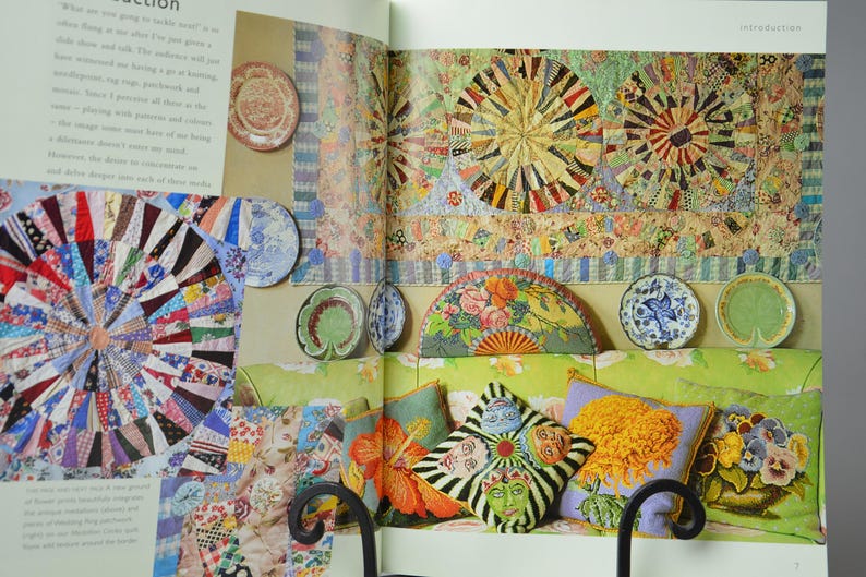 May include: An interior design spread with a patchwork quilt, decorative plates, and patterned cushions. The colour scheme includes red, blue, green, and yellow. The image shows a variety of decorative elements.