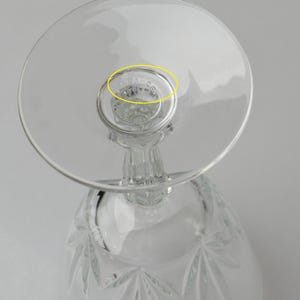 May include: Clear crystal wine glass with a round base and a detailed stem. The bowl of the glass features a starburst pattern. The base of the glass has the etched text "STAFFS".