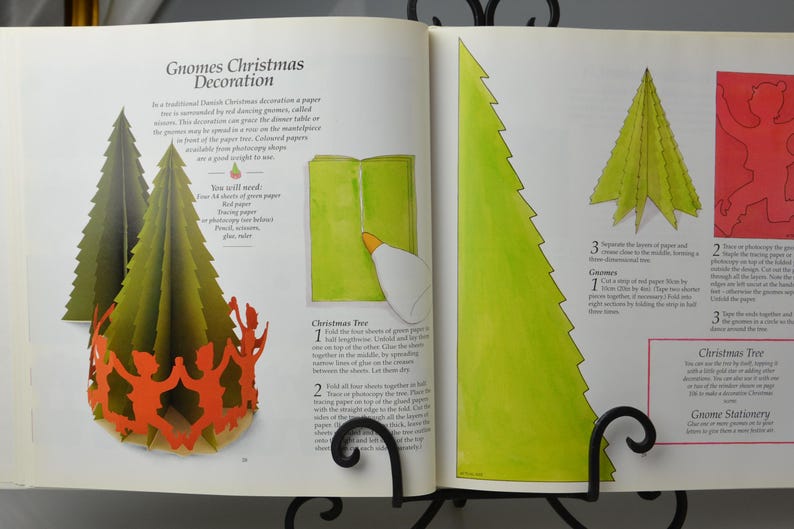 May include: A book with instructions on how to make a paper gnome Christmas decoration. The book shows a green paper gnome with a red hat and a green paper Christmas tree. The text on the page reads "Gnomes Christmas Decoration".