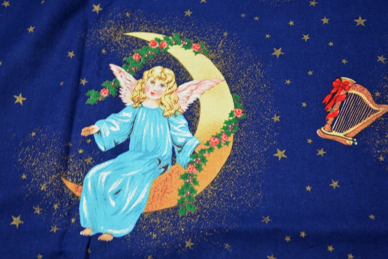 May include: A celestial-themed fabric design featuring a serene angel with blonde hair and blue robes, seated on a crescent moon adorned with roses and holly. A golden harp with a red bow is also depicted against a dark blue starry background.